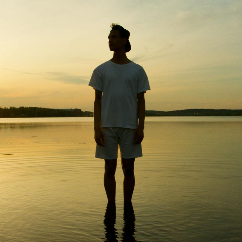 Person meditating peacefully by a lake at sunrise.