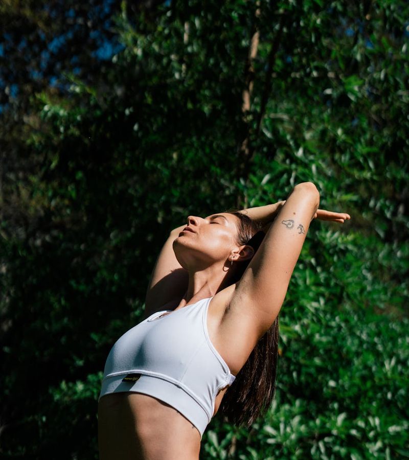 Woman practicing yoga outdoors in a serene natural setting.